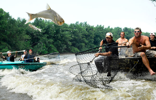 ADAM/JOURNAL STAR  Tim Wells, center, and Rich Pletz, right, both of Canton, lunge forward in hopes of netting flying Asian carp with other teams during Friday afternoon's Redneck Fishing Tournament in Bath.